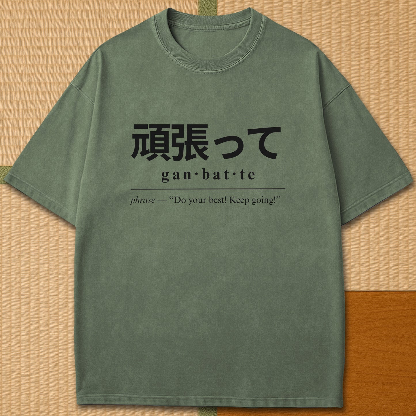 Japanese-inspired cotton Ganbatte Japanese Dictionary T-Shirt in Moss on Comfort Colors 1717, styled in a modern flatlay scene.