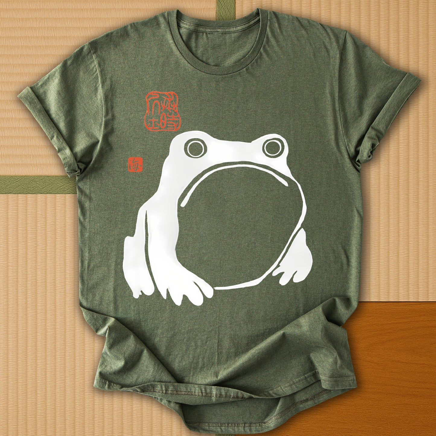 Japanese-inspired cotton Frowning Frog Print T-Shirt in Military Green on Gildan 64000, styled in a modern flatlay scene
