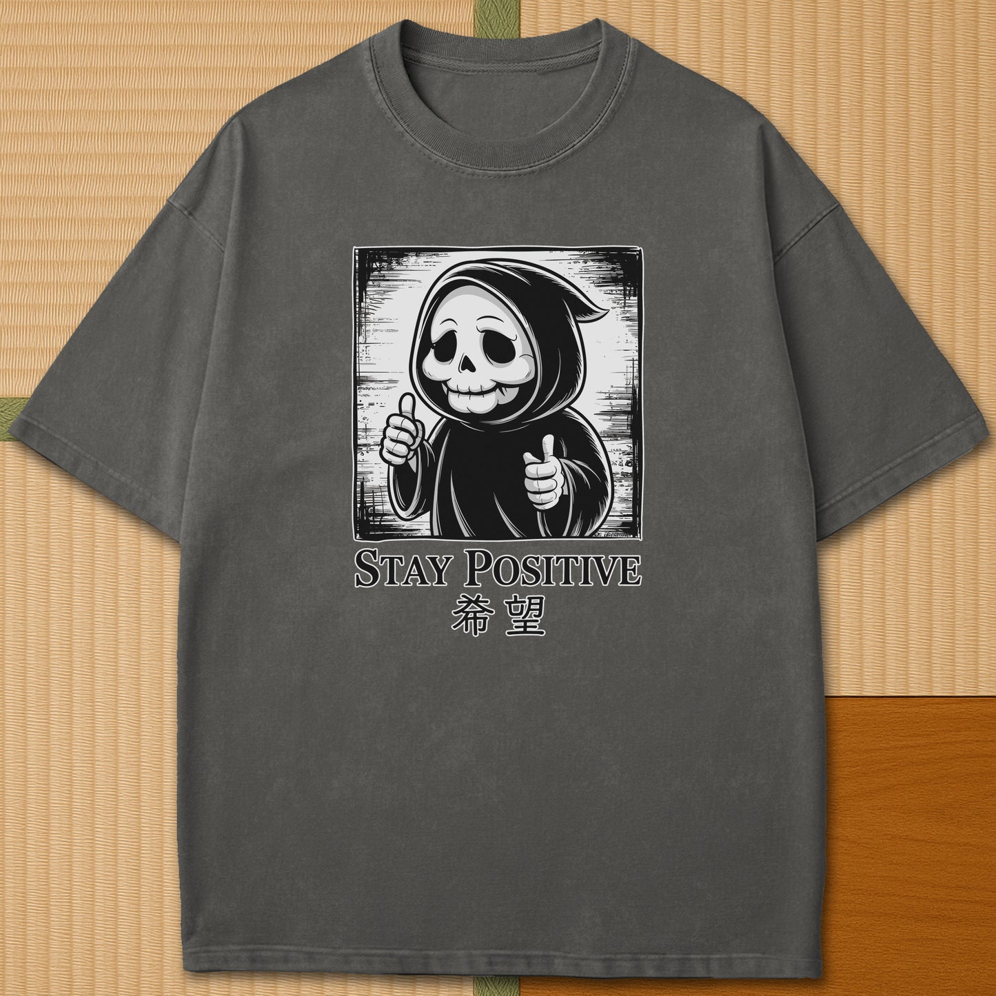 Japanese-inspired cotton Stay Positive Kawaii Grim Reaper T-Shirt in Pepper on Comfort Colors 1717, styled in a modern flatlay scene.