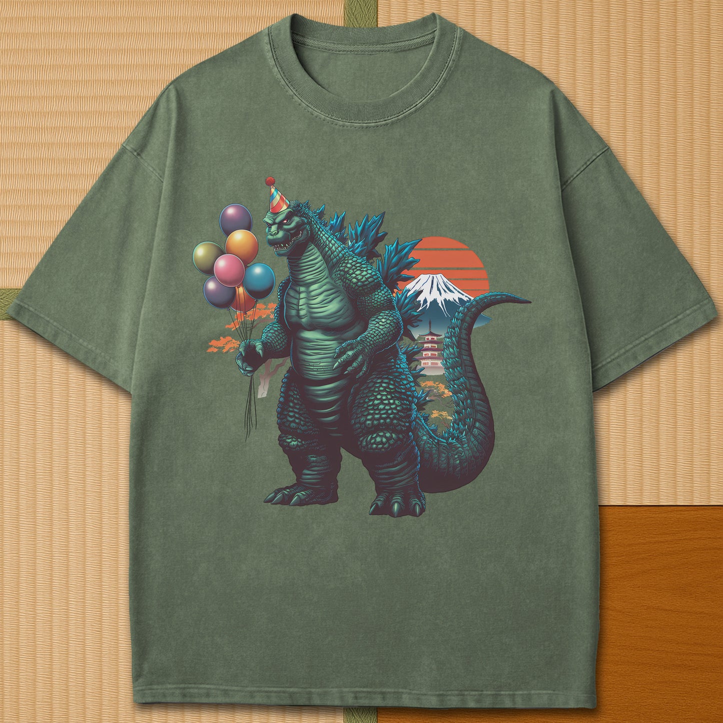 Japanese-inspired cotton Birthday Kaiju T-Shirt in Moss on Comfort Colors 1717, styled in a modern flatlay scene.