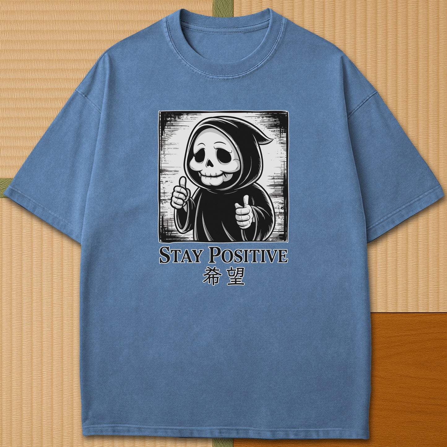Japanese-inspired cotton Stay Positive Kawaii Grim Reaper T-Shirt in Blue Jean on Comfort Colors 1717, styled in a modern flatlay scene.