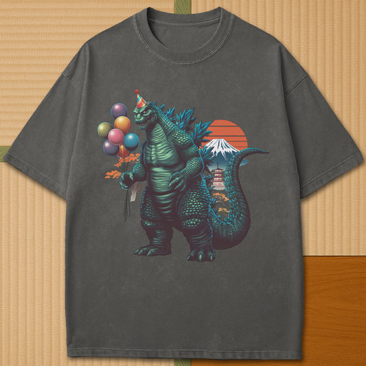 Japanese-inspired cotton Birthday Kaiju T-Shirt in Pepper on Comfort Colors 1717, styled in a modern flatlay scene.