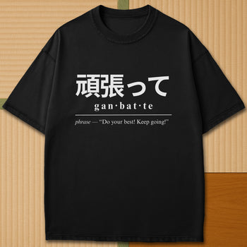 Japanese-inspired cotton Ganbatte Japanese Dictionary T-Shirt in Black on Comfort Colors 1717, styled in a modern flatlay scene.