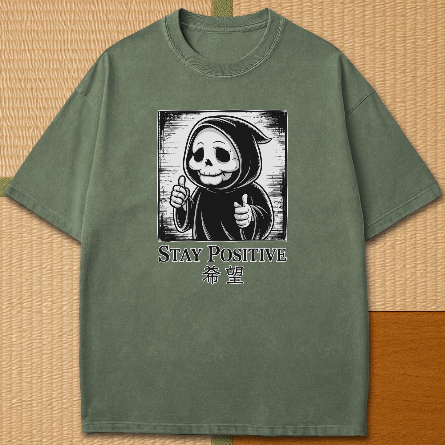 Japanese-inspired cotton Stay Positive Kawaii Grim Reaper T-Shirt in Moss on Comfort Colors 1717, styled in a modern flatlay scene.