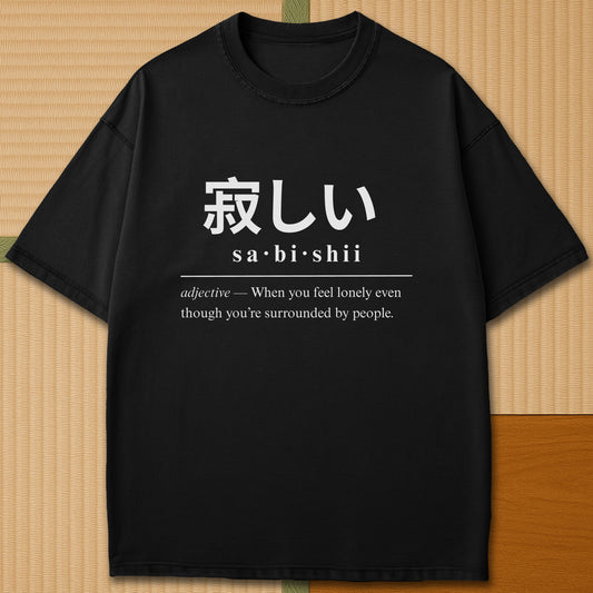 Japanese-inspired cotton Sabishii Japanese Dictionary T-Shirt in Black on Comfort Colors 1717, styled in a modern flatlay scene.