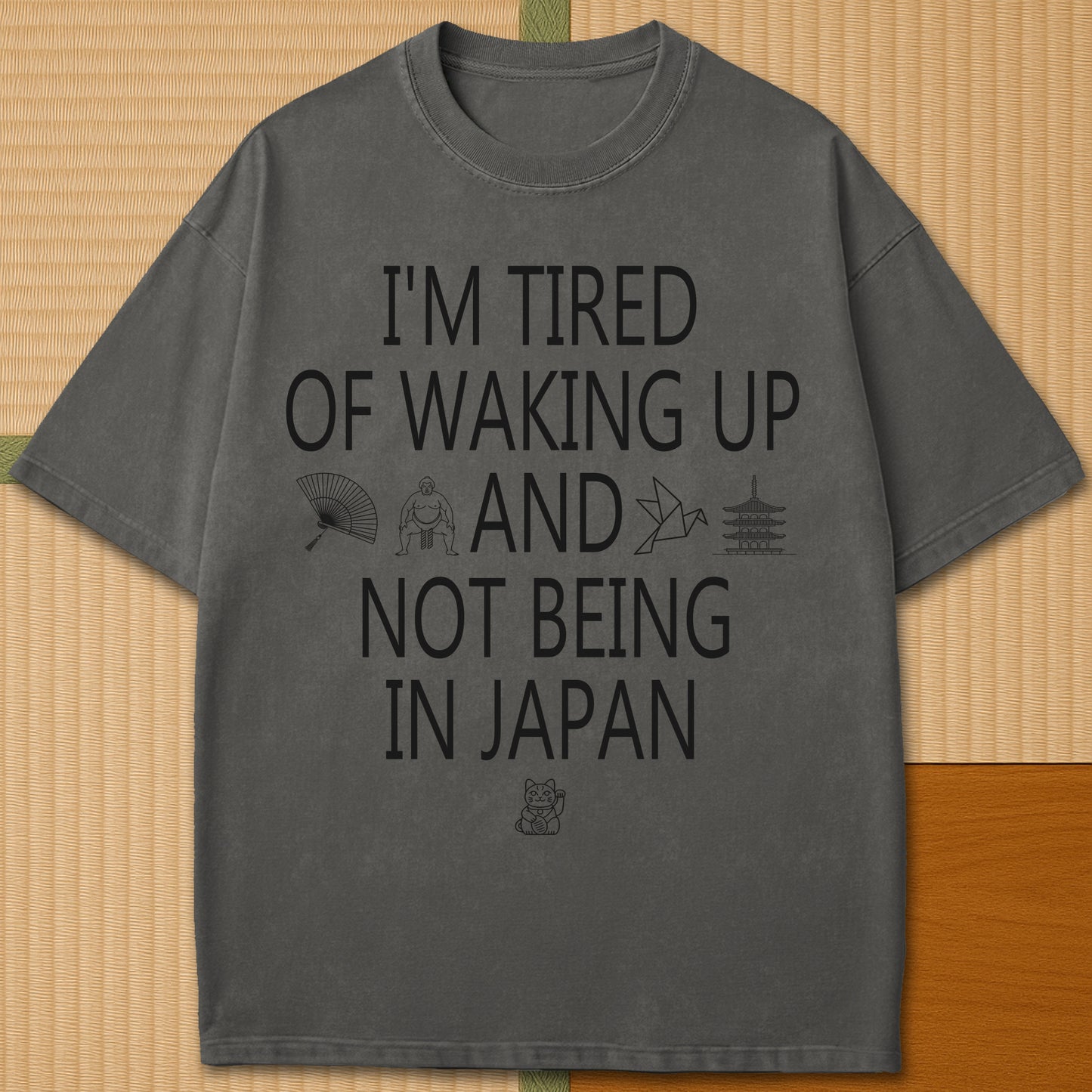 Japanese-inspired cotton Tired Waking Up Not In Japan T-Shirt in Pepper on Comfort Colors 1717, styled in a modern flatlay scene.