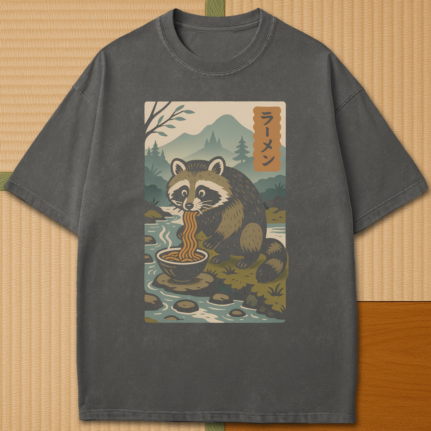 Japanese-inspired cotton Tanuki Slurping Ramen T-Shirt in Pepper on Comfort Colors 1717, styled in a modern flatlay scene.