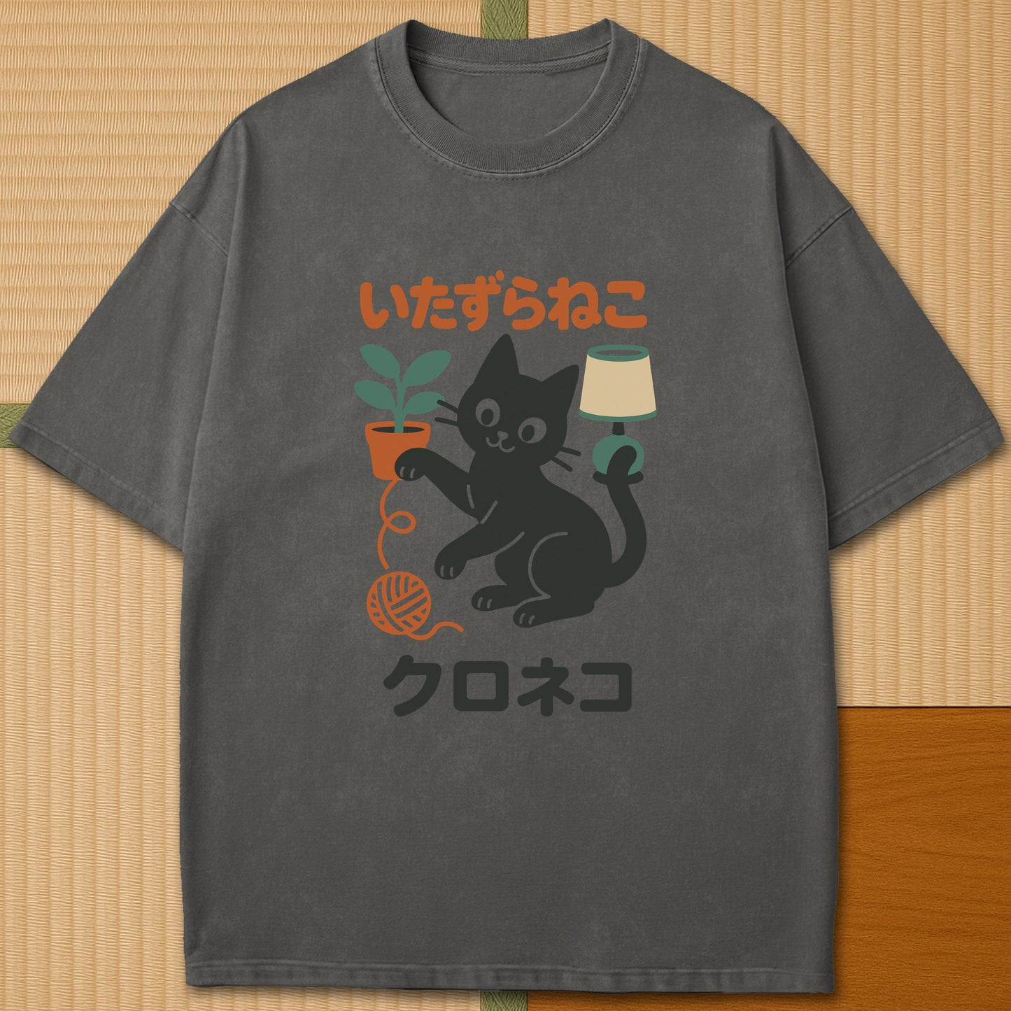 Japanese-inspired cotton Mischievous Black Cat T-Shirt in Pepper on Comfort Colors 1717, styled in a modern flatlay scene.