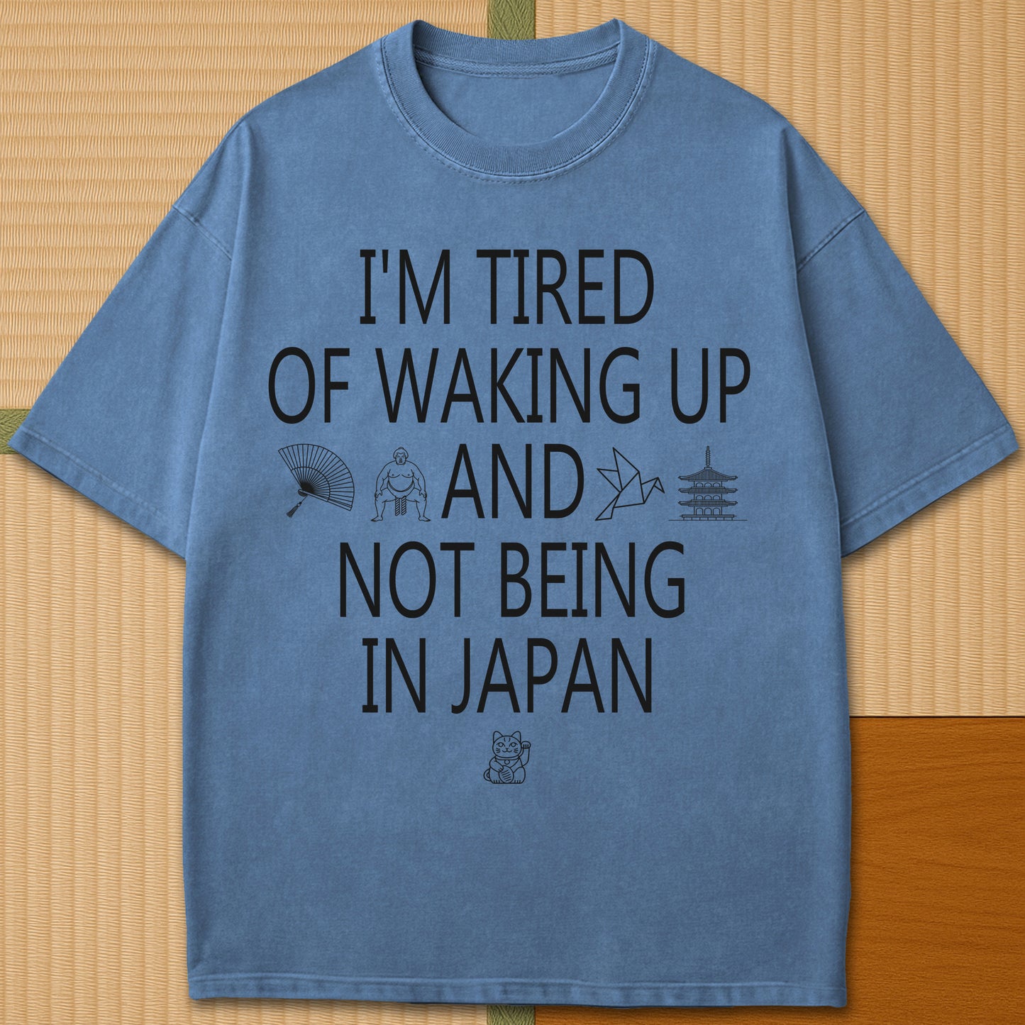 Japanese-inspired cotton Tired Waking Up Not In Japan T-Shirt in Blue Jean on Comfort Colors 1717, styled in a modern flatlay scene.
